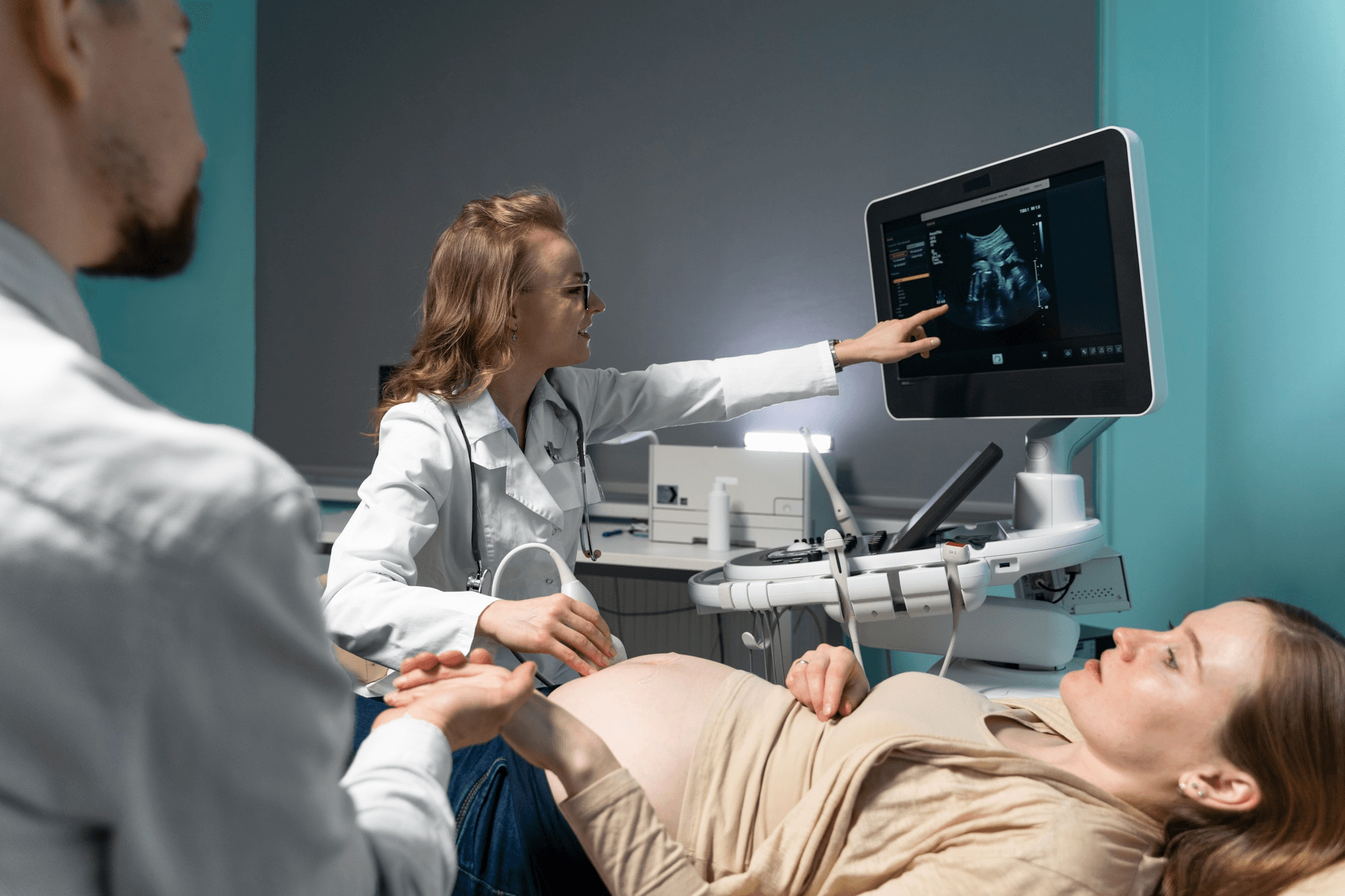 A doctor performs an ultrasound and points to the monitor, underscoring why regular checkups matter during pregnancy.