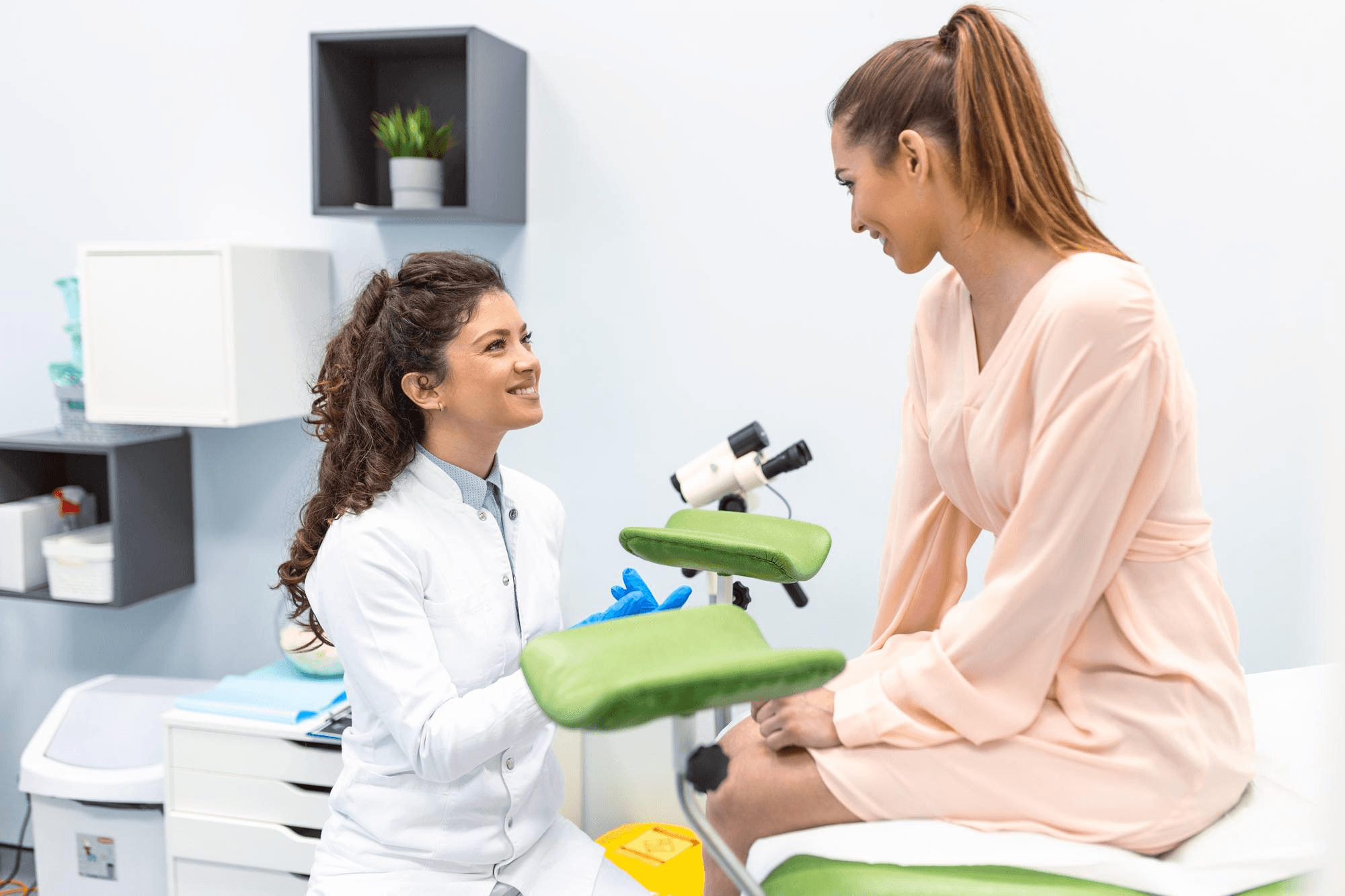A gynecologist talks to a patient before a Pap smear, explaining cervical health and the screening process in the clinic.