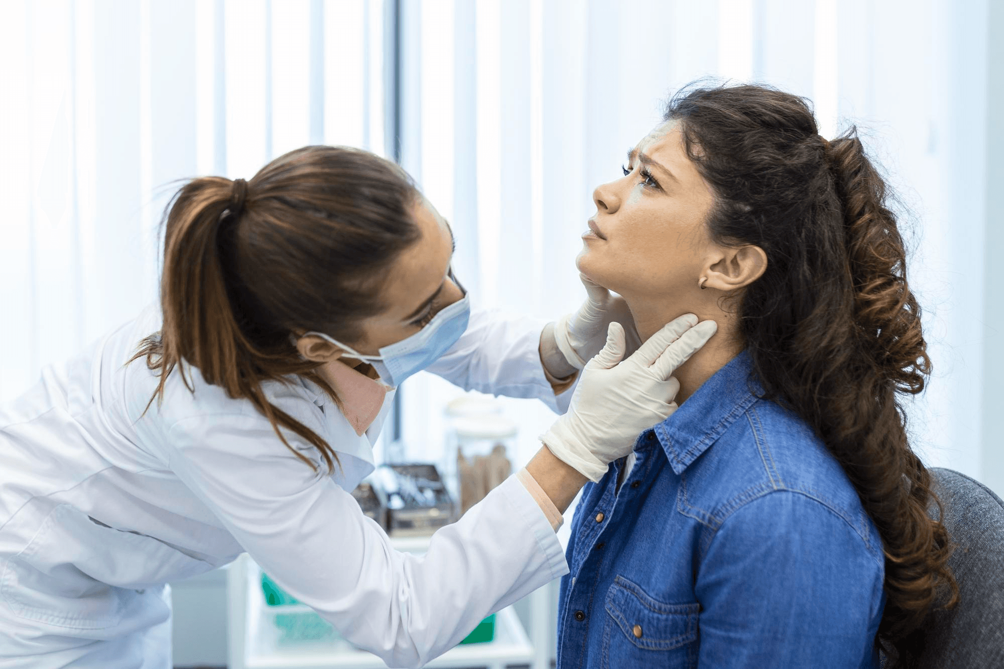 Doctor examining woman's neck for thyroid checkup, assessing gland swelling and symptoms in clinical setting for accurate diagnosis and treatment.
