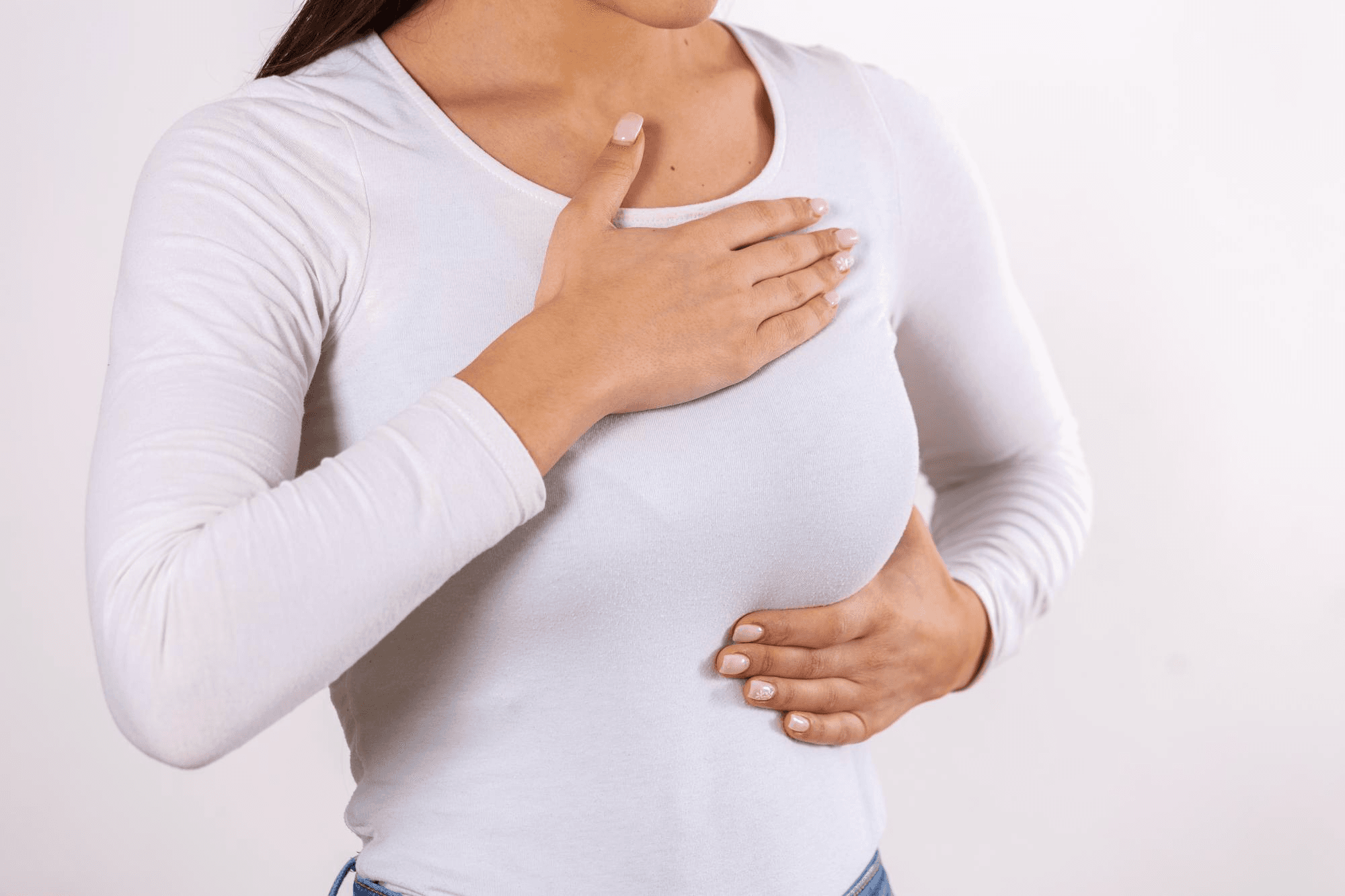 Woman demonstrating breast self-examination: hand on chest, searching for lumps, noticing variations, or irregularities to help identify breast conditions.