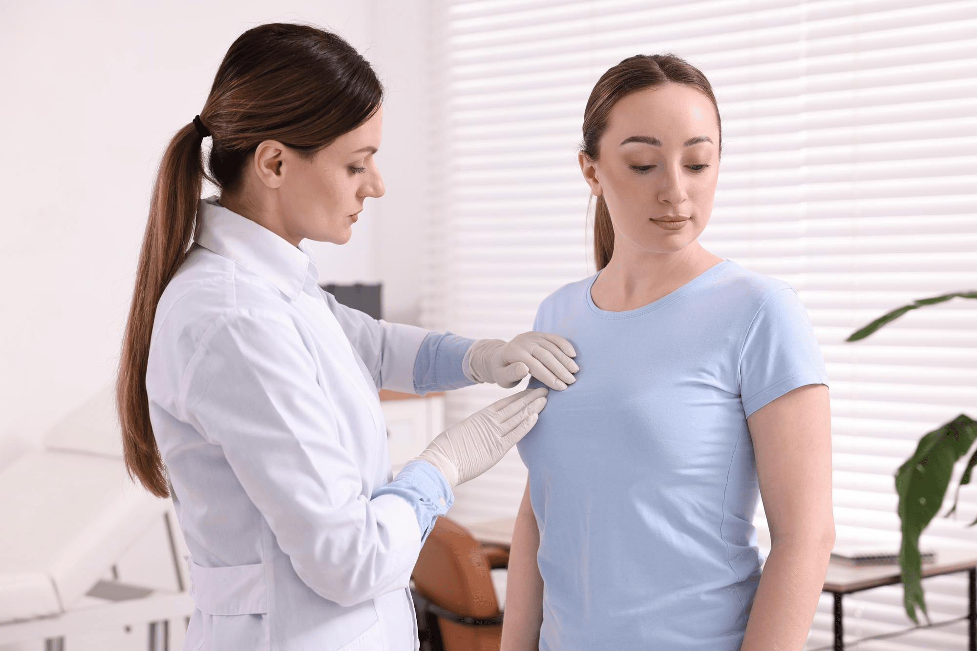 Physician coaching a woman through a proper breast self-examination method, including ways to locate breast lumps and consistently monitor breast health.