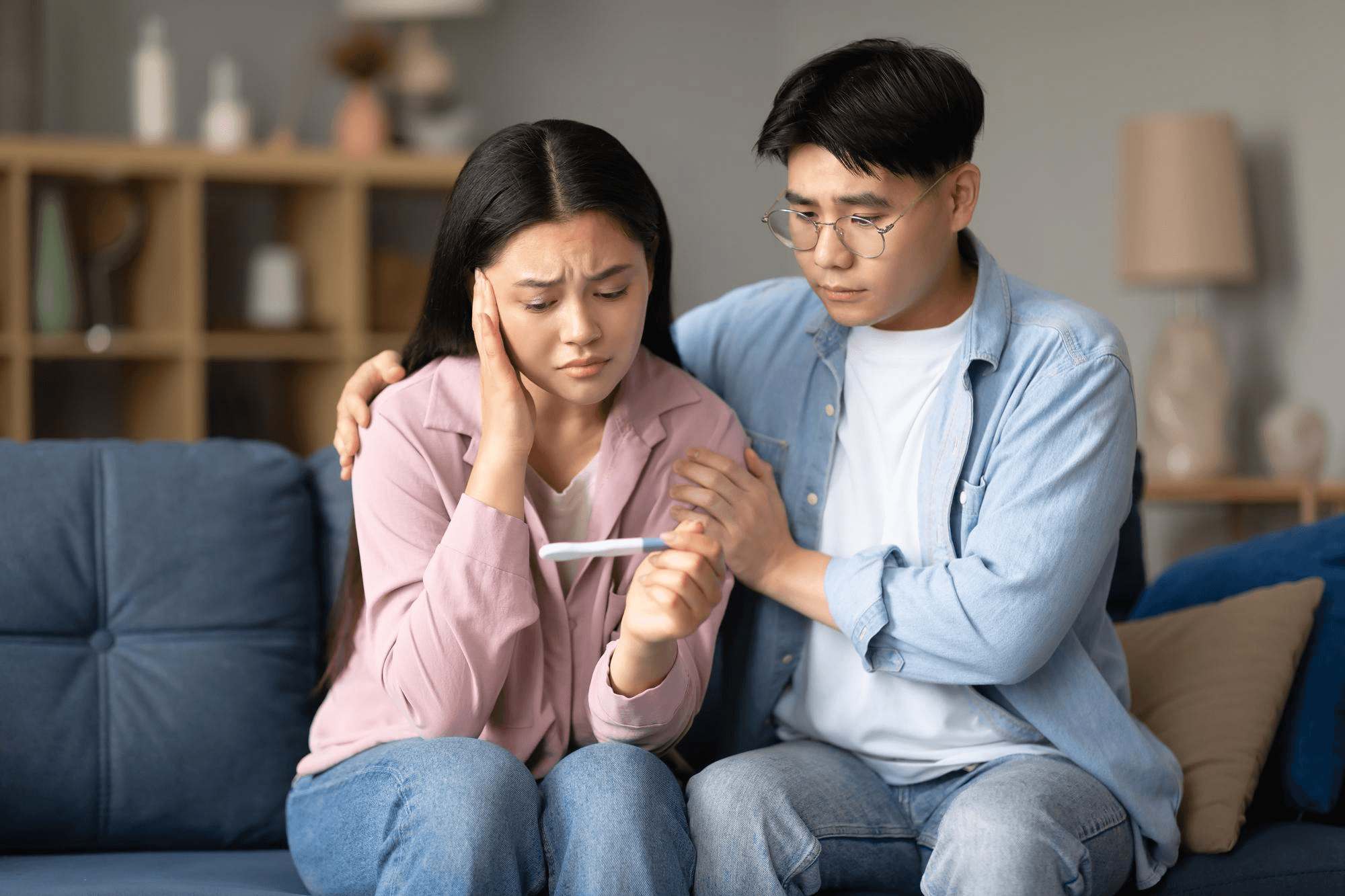 couple appear distressed, worried about having a problem with fertility because of their endometriosis. Sitting in a chair together, showing their concern and lack of hope.