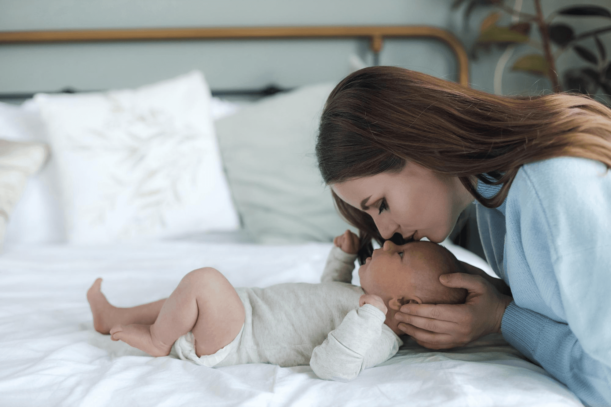 A new mother tenderly kissing her baby's forehead in a moment of intimate bonding and profound maternal love and care