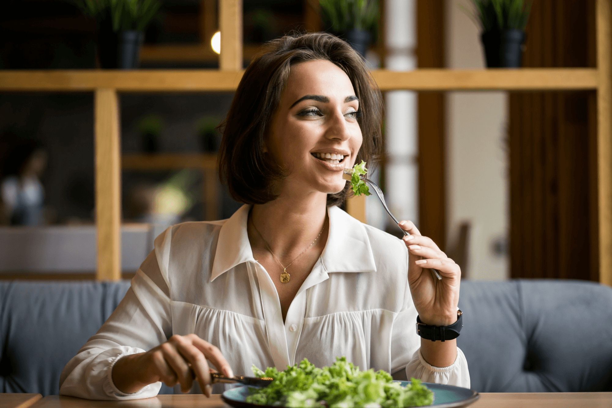 A young woman eating a healthy salad suggests a balanced diet can boost women’s reproductive health and natural infection prevention with a healthy intake of nutrients daily.