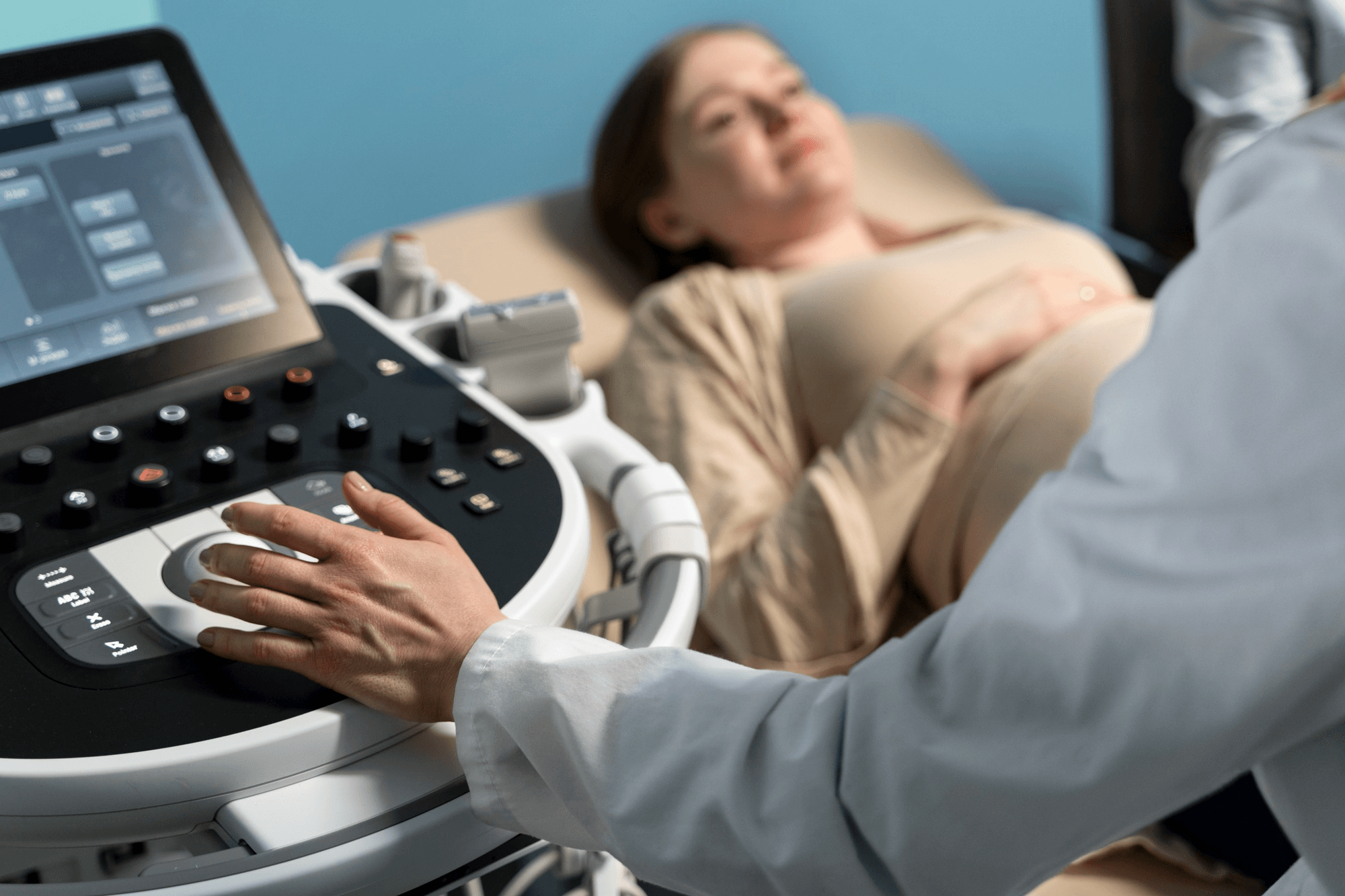A doctor uses an ultrasound machine to examine a pregnant patient during a first-trimester check-up.