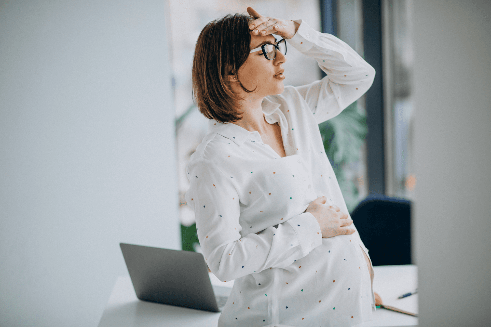 pregnant woman at work leaning on her head from being dizzy