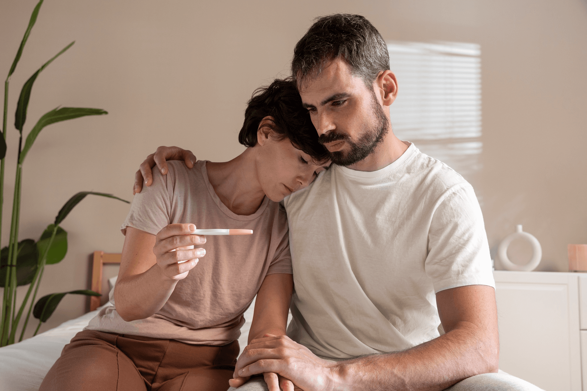 Couple sadly holding a negative pregnancy test, coping with infertility together