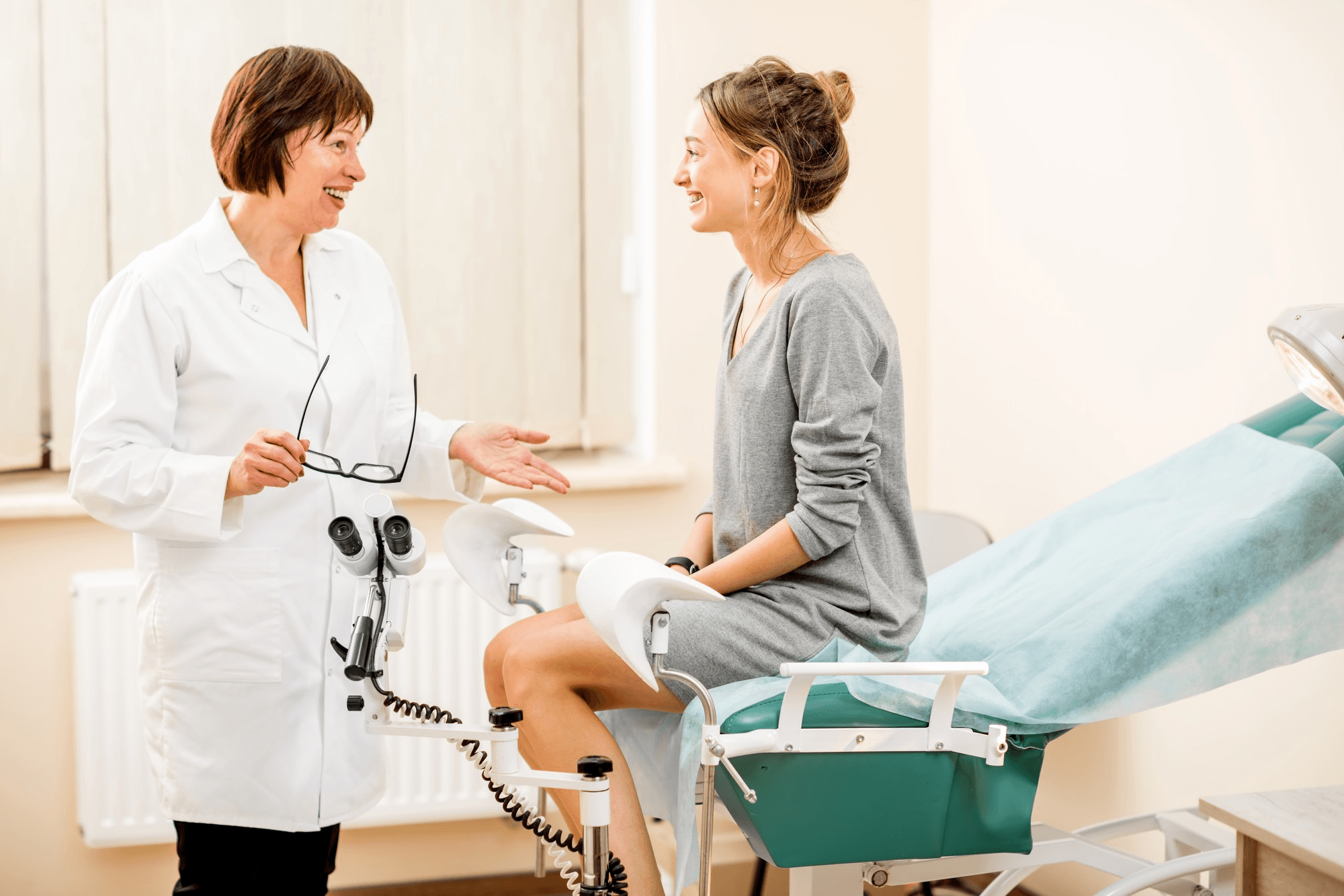 Gynecologist at patient's side explaining diagnosis while performing pelvic exam and showing how blockage in the fallopian tube is treated