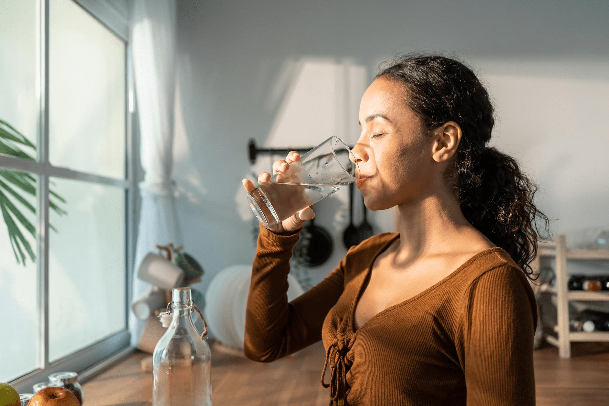 A woman drinking water in a home setting environment.