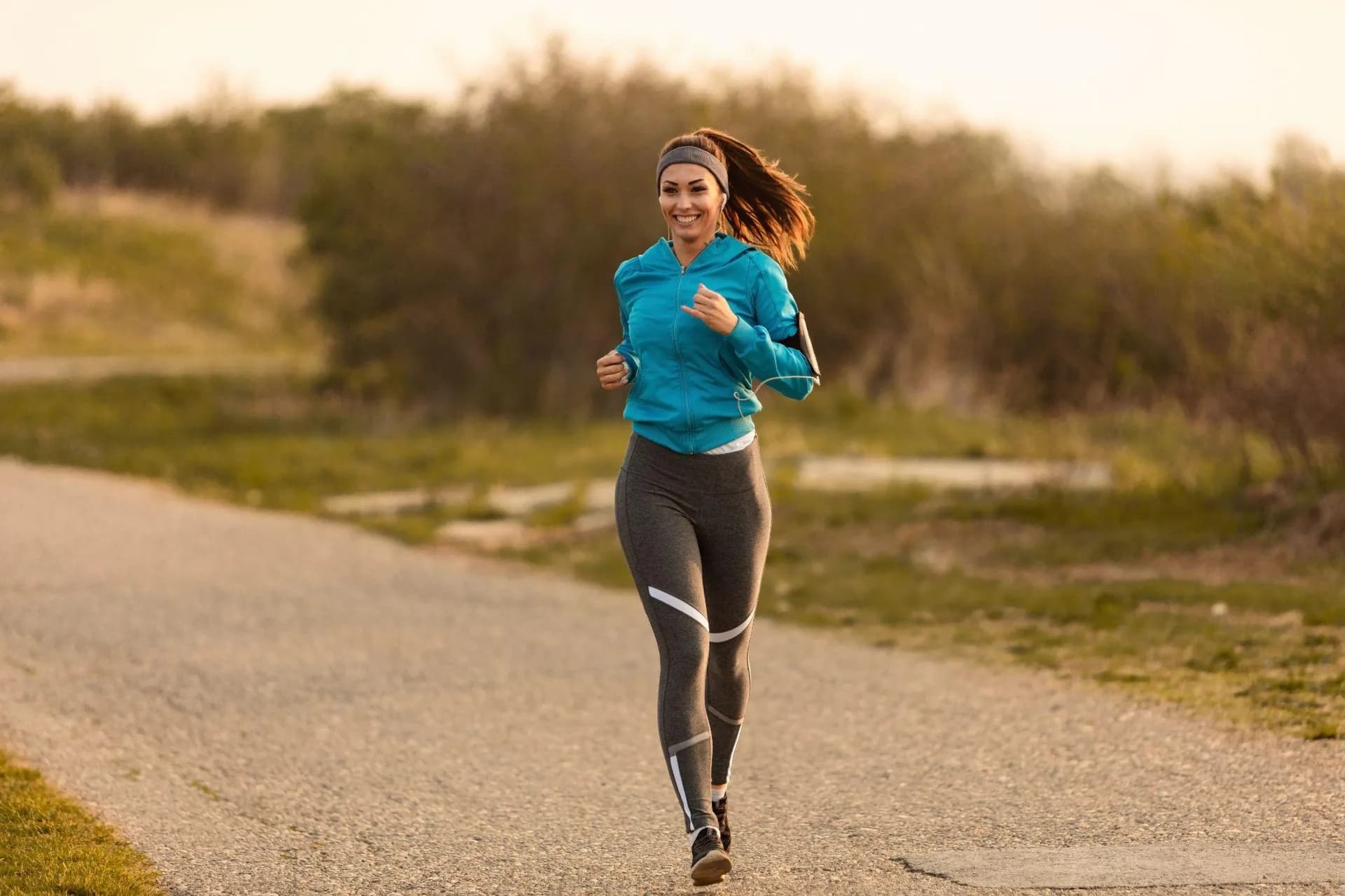 A healthy woman running on a road as part of a regular exercise routine for overall bone health.