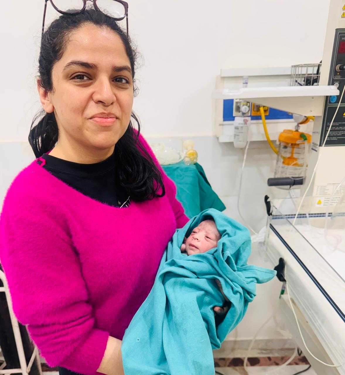 Dr Shachi holding a newborn baby wrapped in teal cloth after delivery at Prakash Hospital Noida